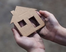 Hands holding a cardboard house