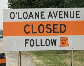 Road closure sign with text "O'Loane Avenue Closed, Follow D1"