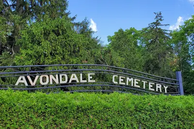 Green trees and hedges, with a sign that reads Avondale Cemetery