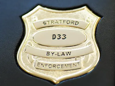 Gold badge in a leather case, with the words Stratford By-law Enforcement on the front
