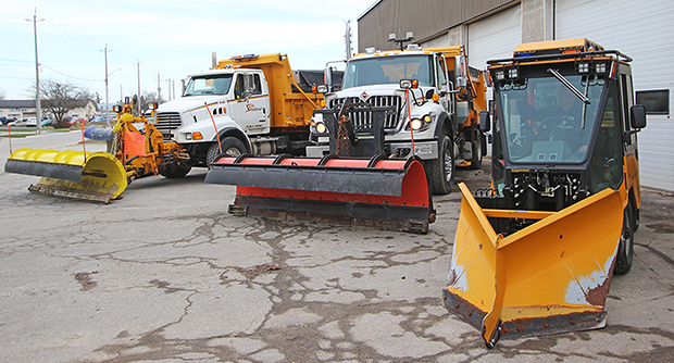 Three winter maintenance with snow plows in front parked in a lot.