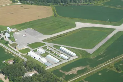 An airport building with runways surrounded by green fields and trees