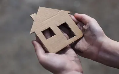 Hands holding a cardboard cutout of a house
