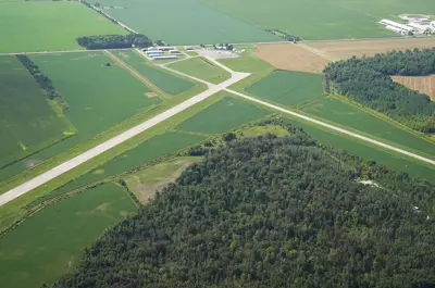 An airport building with runways surrounded by green fields and trees