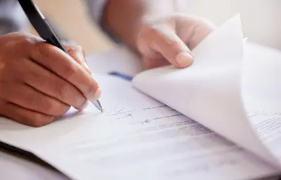Person holding a pen to sign papers