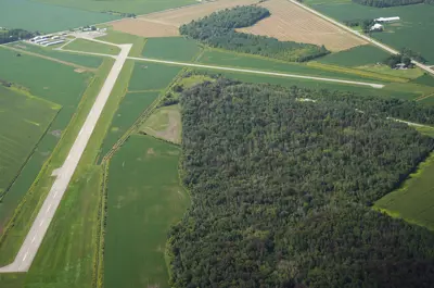 An airport building and runways surrounded by green fields and trees