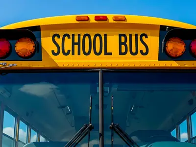 Front view of yellow school bus against a blue sky